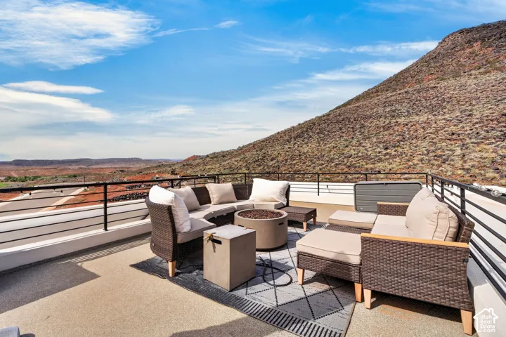 Rooftop deck featuring a textured concrete surface, black metal horizontal railing, and expansive mountain terrain