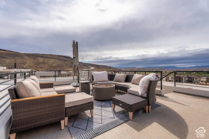 Rooftop terrace featuring concrete-finish flooring, integrated metal railings, and a built-in circular fire pit, set against a mountain backdrop