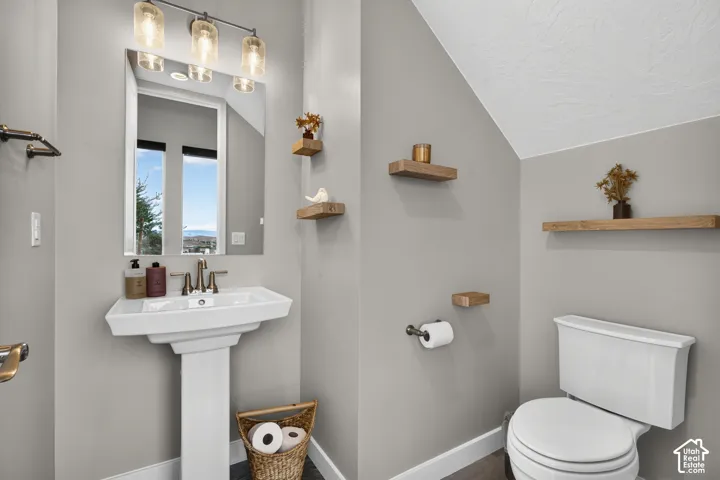 Pedestal sink with metallic faucet, rectangular wall-mounted wood shelving, and three-light vanity fixture