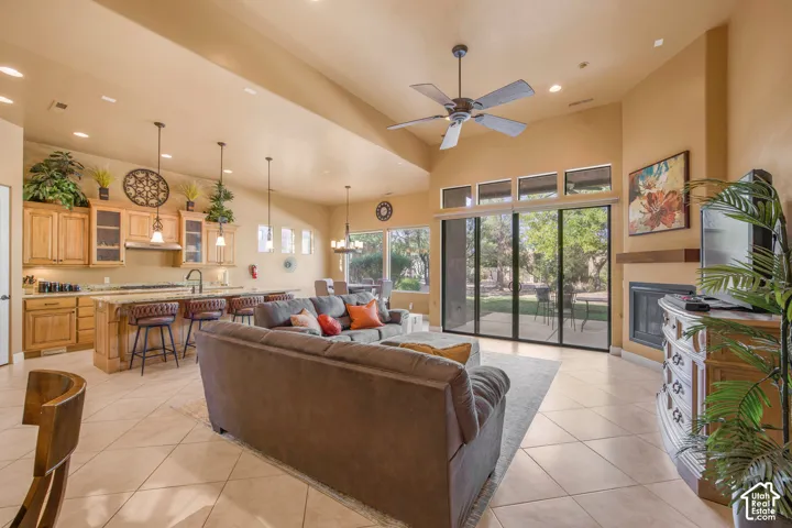 Open-concept living area featuring a vaulted ceiling with ceiling fan, recessed and pendant lighting, and expansive glass sliding doors overlooking mature landscaping