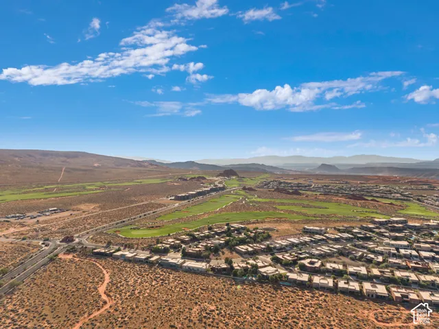 Expansive desert landscape featuring a residential community, green golf course, and distant mountain ranges