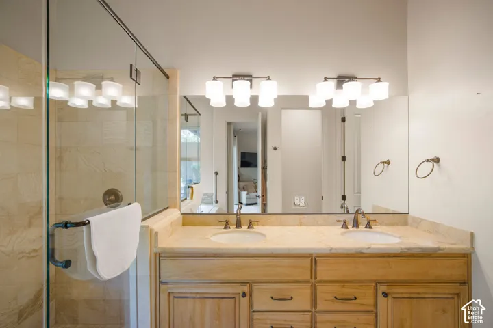 Dual vanity with individual sinks, integrated wall mirror, and a glass-enclosed shower with tile surround