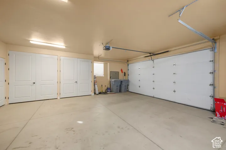 Spacious garage with a sectional garage door, concrete flooring, and multiple interior access doors