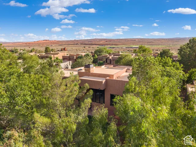 Terracotta-hued stucco exterior with multiple large windows, chimney stack, and mature tree landscaping