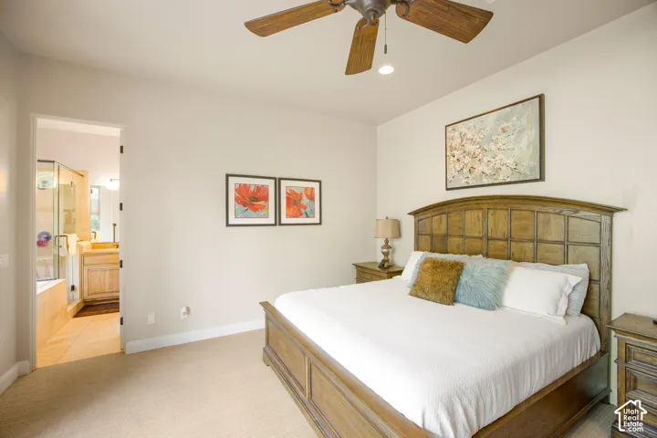 Recessed ceiling light, wood-finish ceiling fan, wood-finish bed frame, carpet flooring, and a stone-finish tub surround