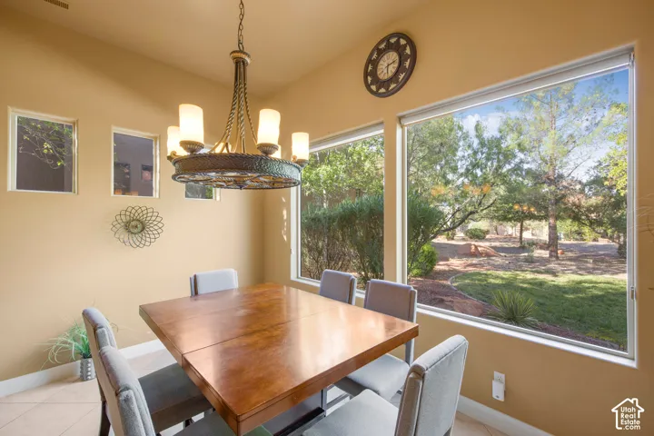Bright dining room showcasing a wood-finish dining table, upholstered chairs, and a bronze chandelier with cylindrical glass shades