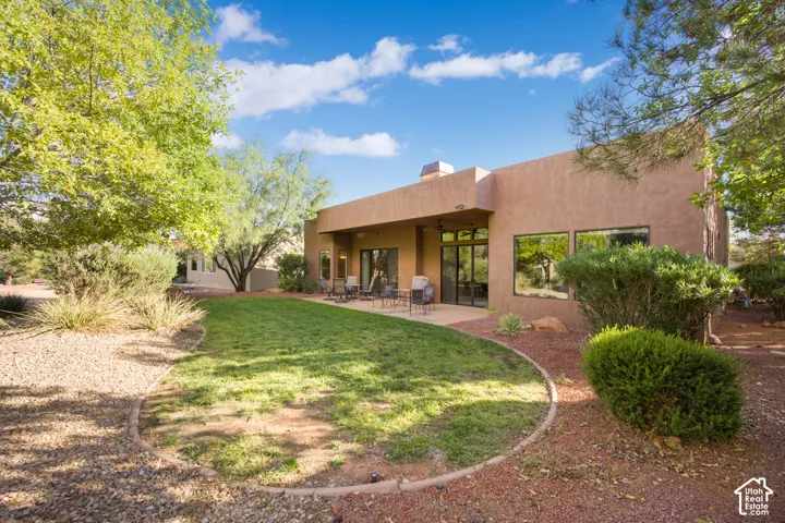 Expansive backyard featuring a manicured lawn, established landscaping, and a covered patio
