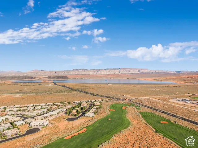 Expansive golf course with manicured greens, surrounding residential area, and a large body of water in the background