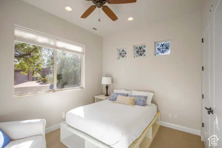 Recessed lighting, ceiling fan with wood-finish blades, three decorative glass block windows, and wood-finish flooring