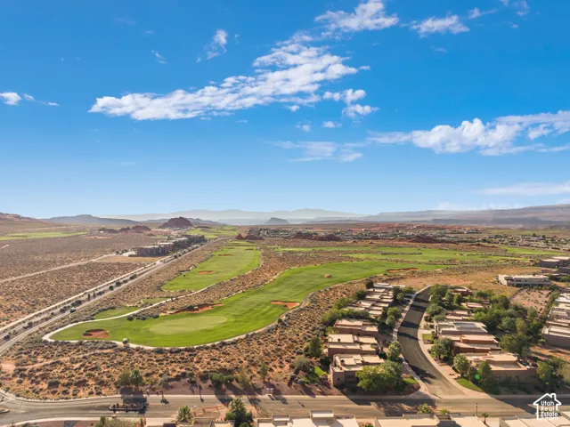 Expansive desert landscape featuring a golf course, residential structures, and a winding road