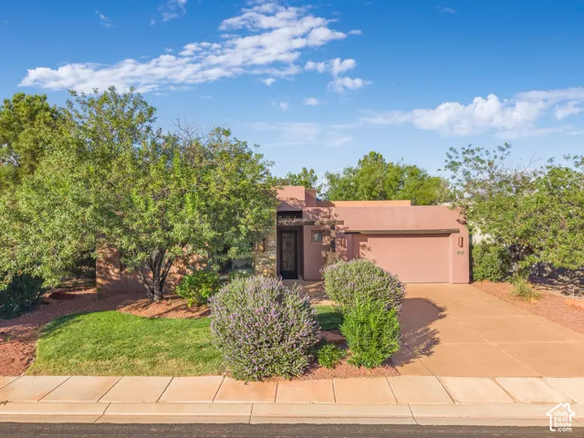 Southwestern architectural style with a flat roofline, an attached garage, and a concrete driveway