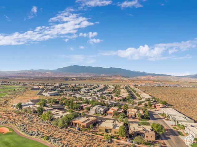 Expansive residential area featuring numerous single-family homes, integrated within a desert landscape, with a prominent mountain range backdrop