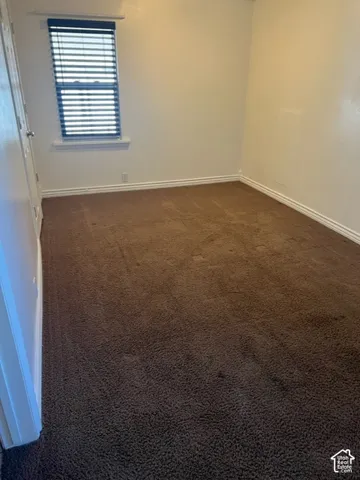 Neutral-toned walls, wall-to-wall carpeting, and a window with horizontal blinds