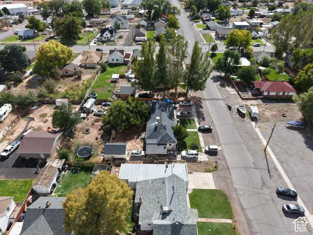 Aerial view of a residential lot featuring established mature trees, a detached storage structure, and fenced perimeter