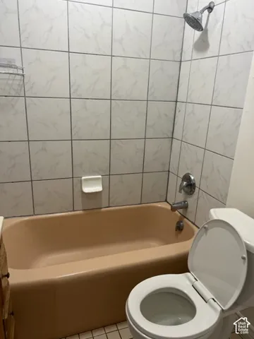 Full-height wall tile surrounding a bathtub with chrome hardware and a built-in ceramic soap dish