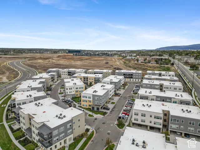 Aerial perspective of a multi-building residential complex featuring modern architecture, flat rooflines, a mix of light-colored exterior siding and stone veneer, and paved street access