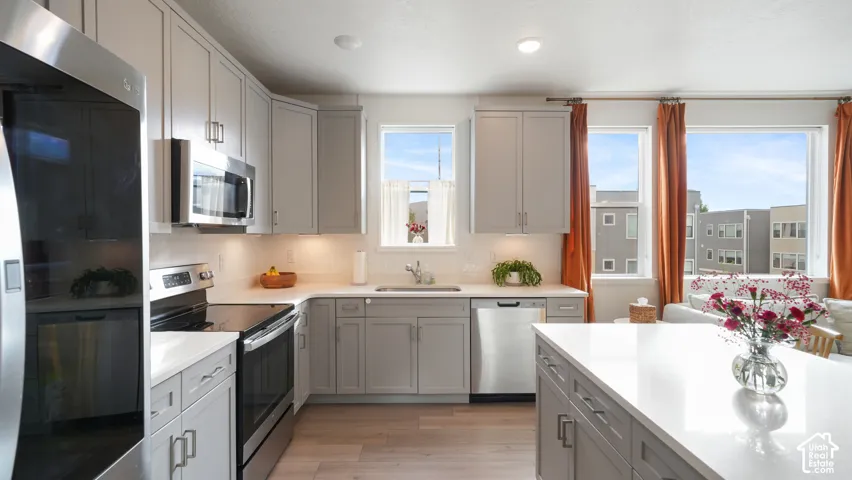 Kitchen featuring shaker-style cabinetry, a central island with a solid surface countertop, stainless steel appliances, and wood-finish flooring