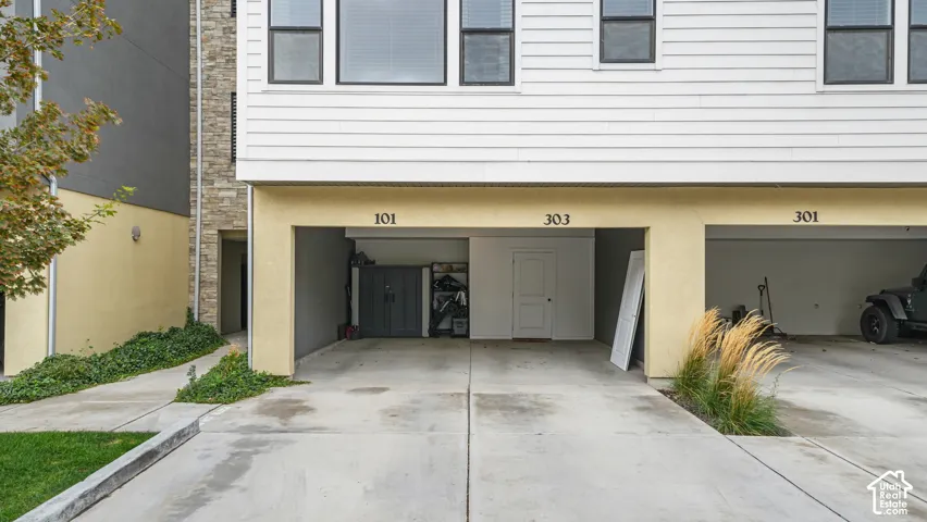 Multi-level exterior featuring horizontal siding, stone veneer accents, and ground-level covered parking spaces