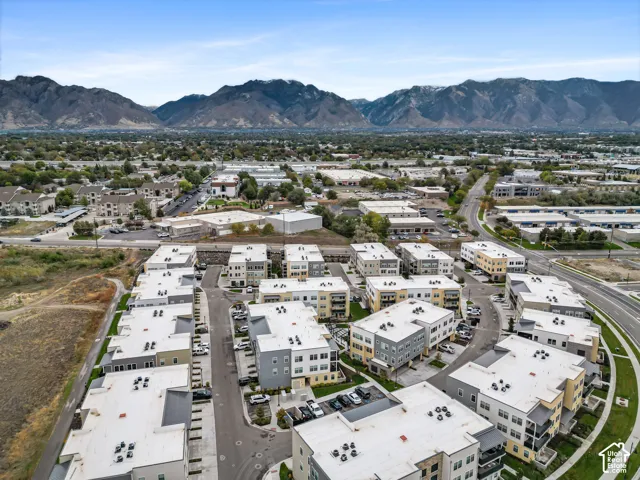 Aerial perspective of a multi-unit residential community featuring modern architectural facades, flat roofing systems, private internal roadways, and a prominent mountain range backdrop