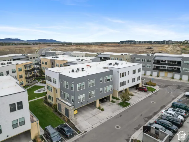 Multi-story residential complex featuring contemporary stucco and siding exterior, flat roof lines, integrated ground-level garage parking, and manicured green space