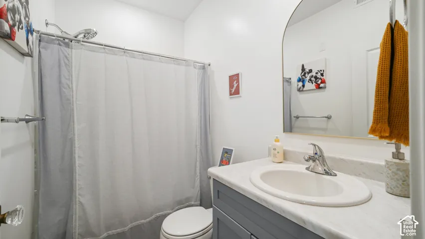 Bathroom featuring a vanity with a stone-finish countertop, undermount oval sink, chrome finish faucet, arched mirror, and shower-tub combination