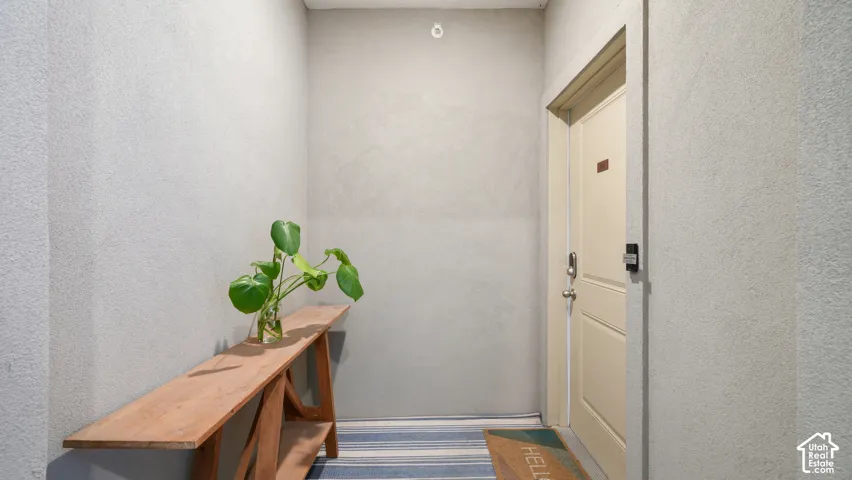 Neutral interior entryway featuring textured wall finishes and a solid core paneled door with integrated electronic lock hardware