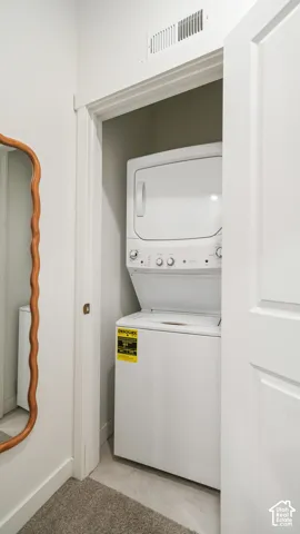 Laundry closet featuring a white stacked washer and dryer unit behind a paneled door