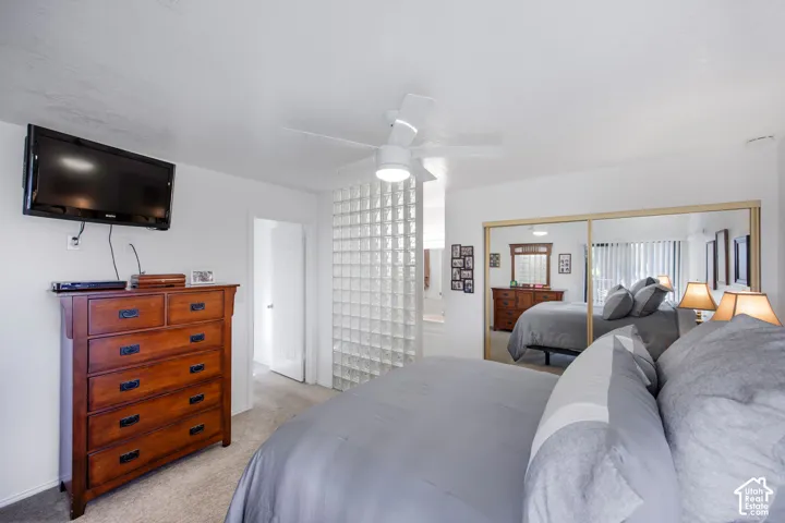 Interior space featuring a glass block partition, ceiling fan with integrated lighting, and dual sliding mirrored closet doors