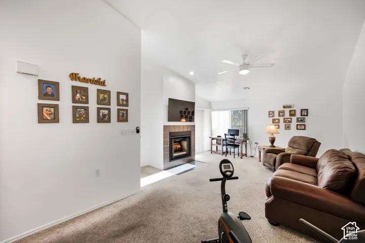 Living area featuring a tile-surround fireplace, vaulted ceiling, and overhead ceiling fan