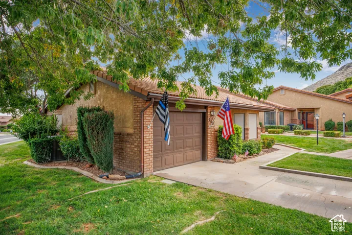 Stucco and brick exterior featuring a tiled roof, concrete driveway, and attached garage
