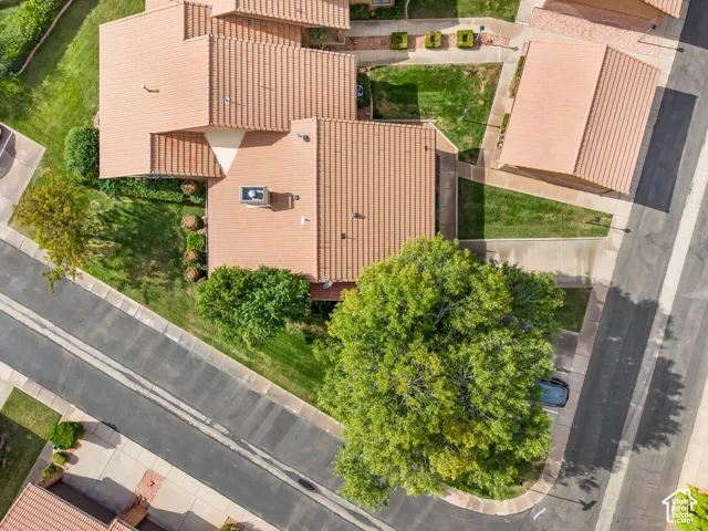 Aerial perspective featuring a tile roof, mature landscaping, concrete walkways, and an attached garage