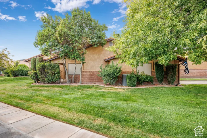 Exterior featuring stucco and brick facade, mature trees, and landscaped grounds
