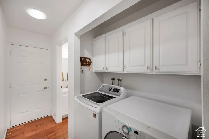 Laundry area featuring white shaker-style wall-mounted cabinetry, wood-finish flooring, and recessed ceiling lighting