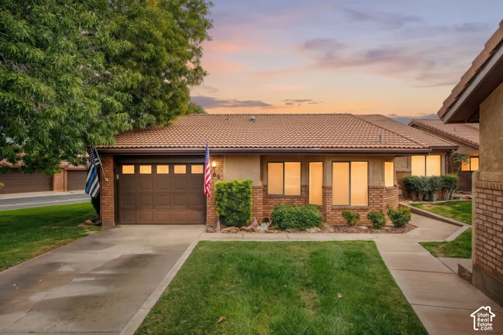 Single-story residence featuring a tile roof, brick facade accents, concrete driveway, and attached garage