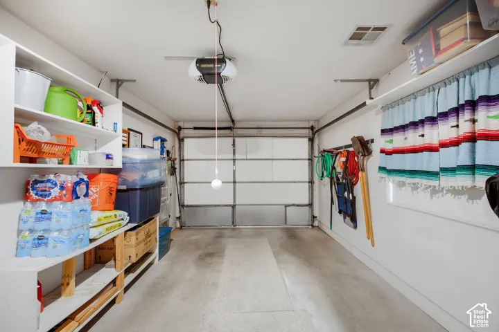 Single-car garage featuring a sectional overhead door, built-in wall shelving, and an integrated wall-mounted gear track system