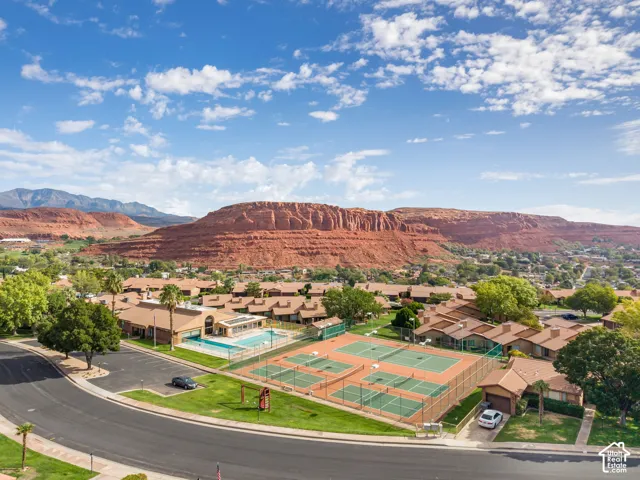 Community amenities featuring a swimming pool, multiple fenced tennis courts, and landscaped grounds against a backdrop of red rock formations