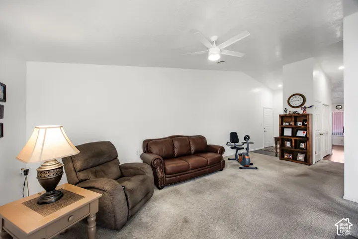 Vaulted ceilings featuring a central white ceiling fan and carpeting throughout