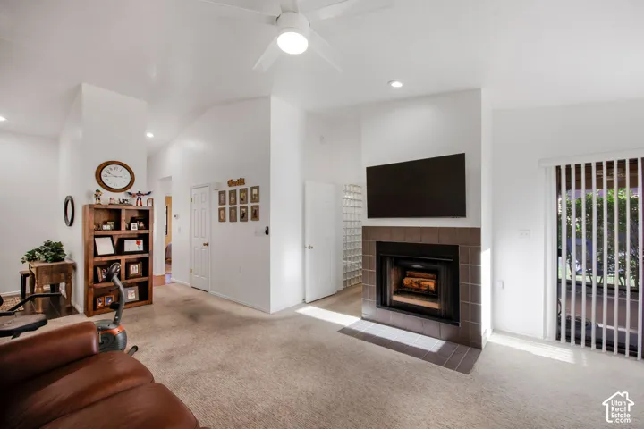 Vaulted ceilings, fireplace with tile surround, built-in shelving, glass block wall, and sliding glass door