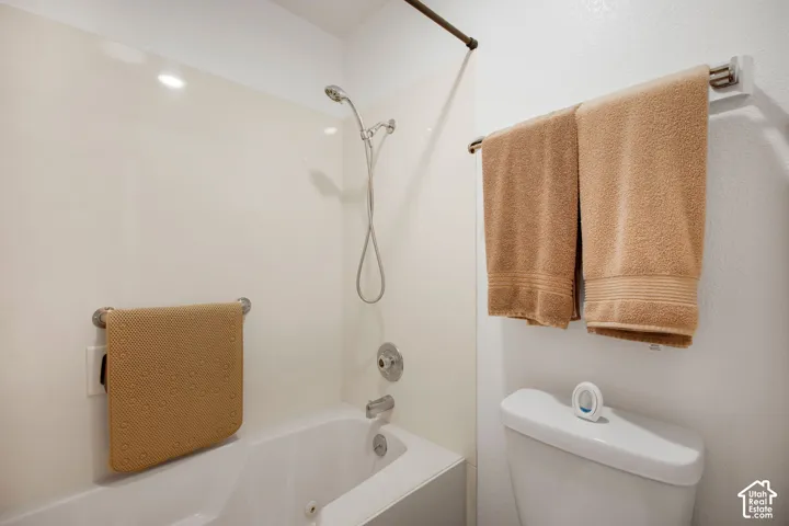 Bathtub enclosure featuring solid-surface surround, integrated shower plumbing, polished metal fixtures, and a dual-purpose towel bar