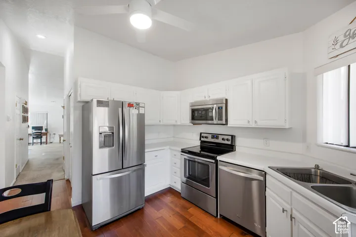Kitchen featuring white cabinetry, wood-finish flooring, stainless steel appliances, and a built-in ceiling fan
