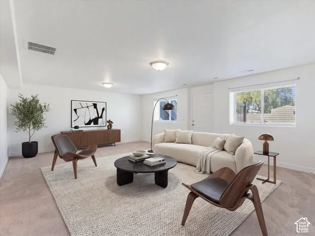 Expansive living room featuring neutral carpeting, flush-mount lighting and a walk-out door