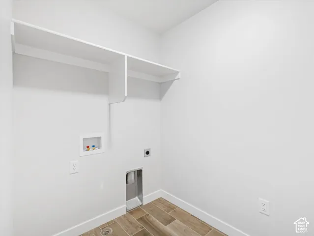 Laundry space featuring wood-look tile flooring & built-in white shelving