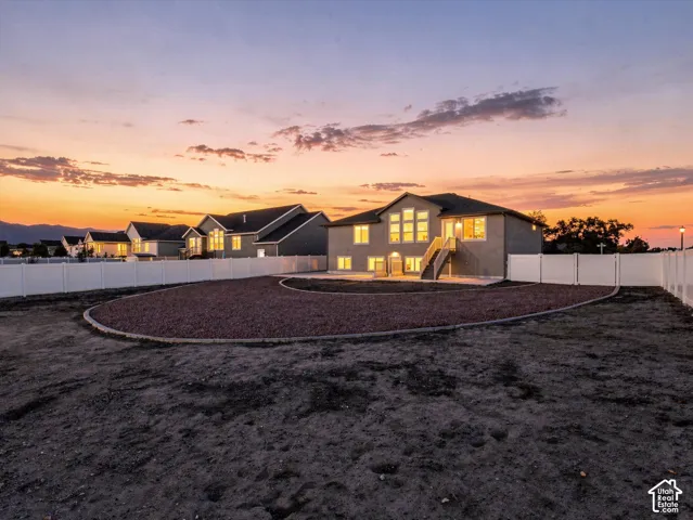 Backyard featuring a concrete patio, gravel landscaping, white vinyl fencing, and rear exterior stairs