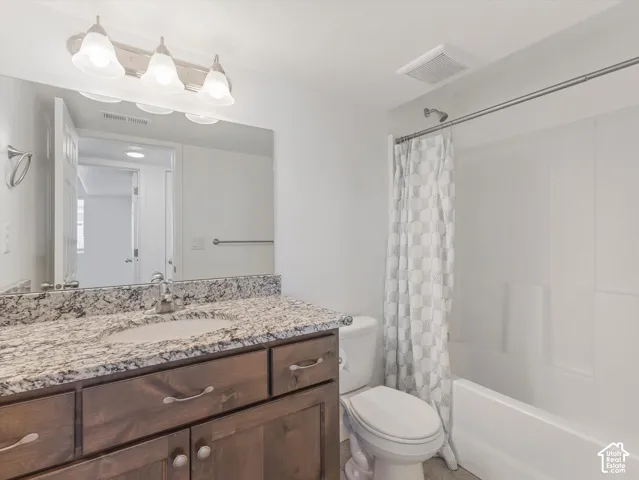 Bathroom featuring a wood-tone vanity, granite countertop and a full-height shower and tub combination