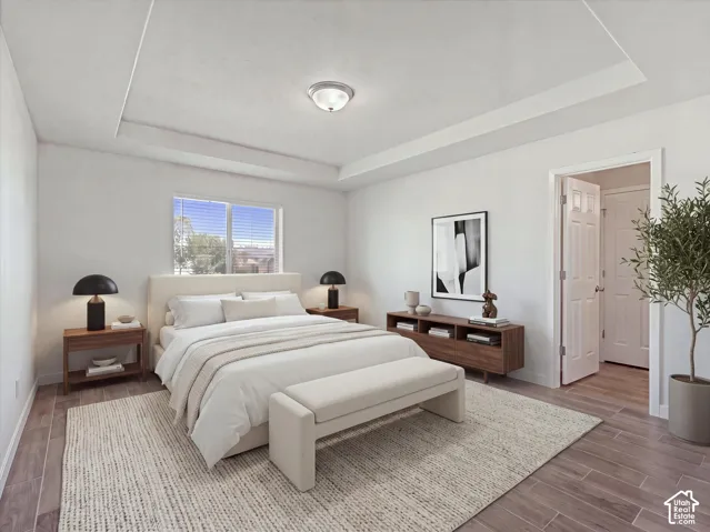 Primary bedroom featuring a tray ceiling & wood-finish tile flooring