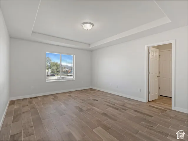 Primary bedroom featuring a tray ceiling & wood-look tile flooring