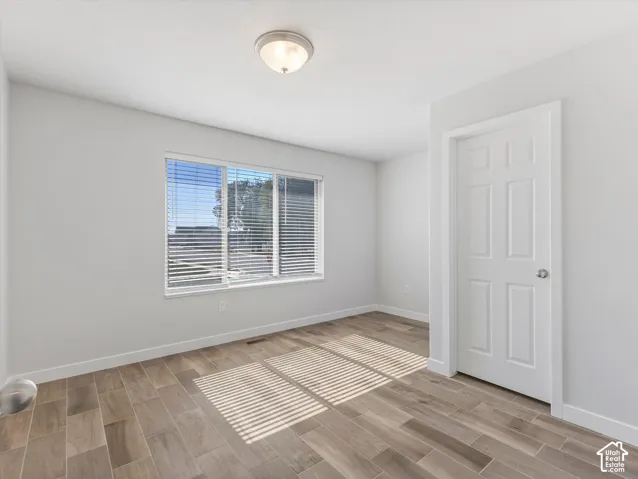 Bedroom #3 featuring wood-finish tile flooring, flush mount light fixture and a walk-in closet