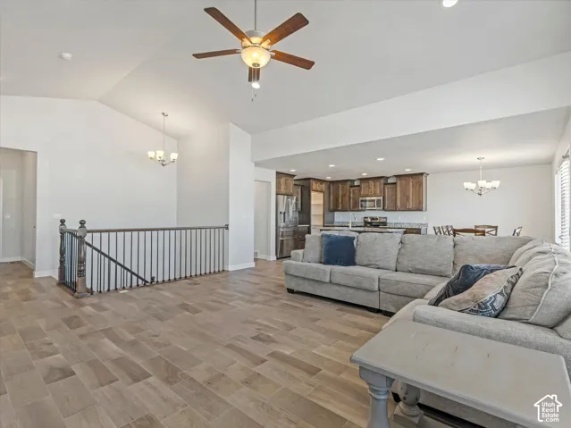 Vaulted ceiling with wood-finish tile flooring, metal staircase railing with a wood handrail and recessed lighting,