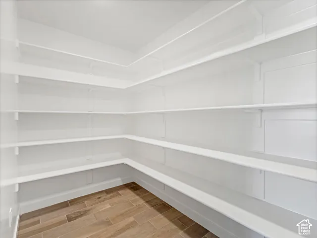 Walk-in pantry featuring white multi-tiered shelving and wood-look tile flooring