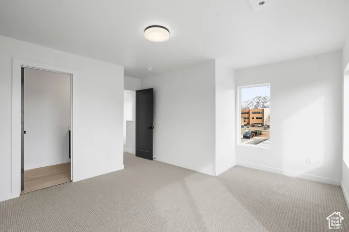 Neutral interior featuring wall-to-wall carpeting, flush-mount circular lighting, contrasting dark-toned interior doors, and window-framed mountain scenery